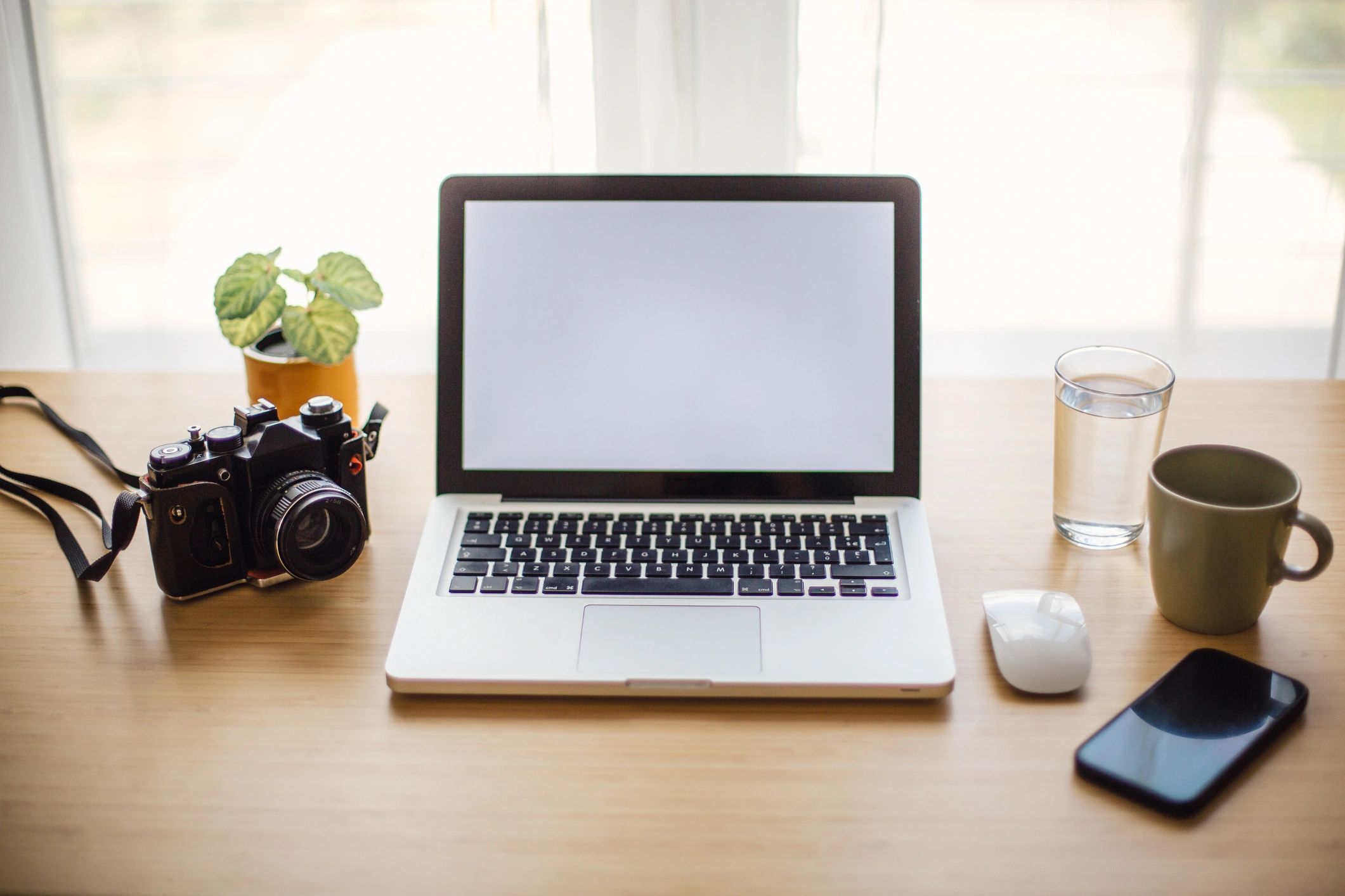 Minimal creative desk with laptop and camera